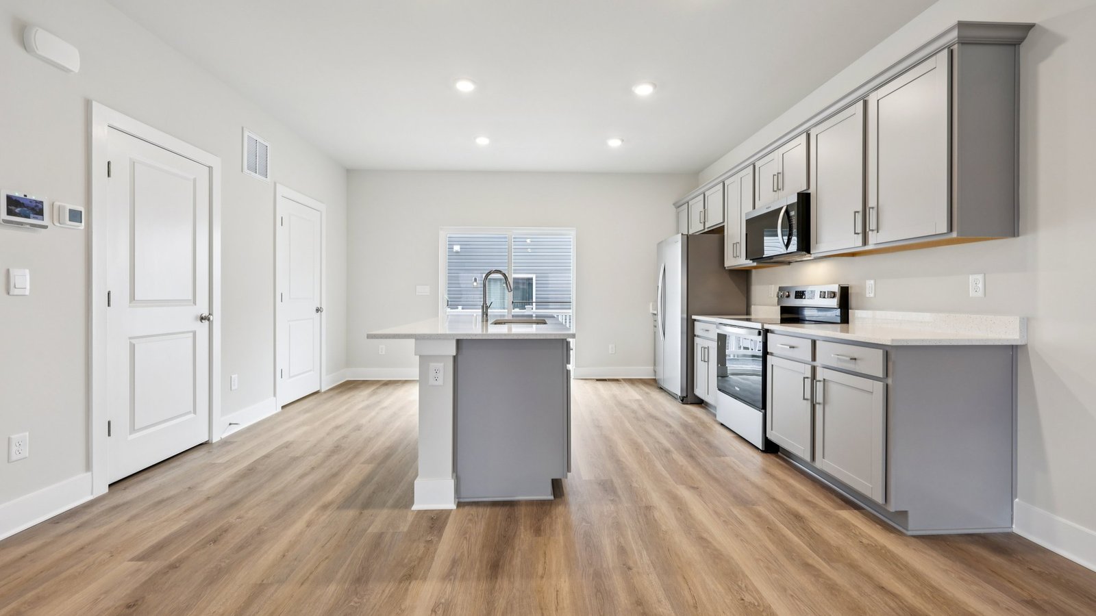 Kitchen and dining — white cabinetry, round table, and island beside window and sliding doors.