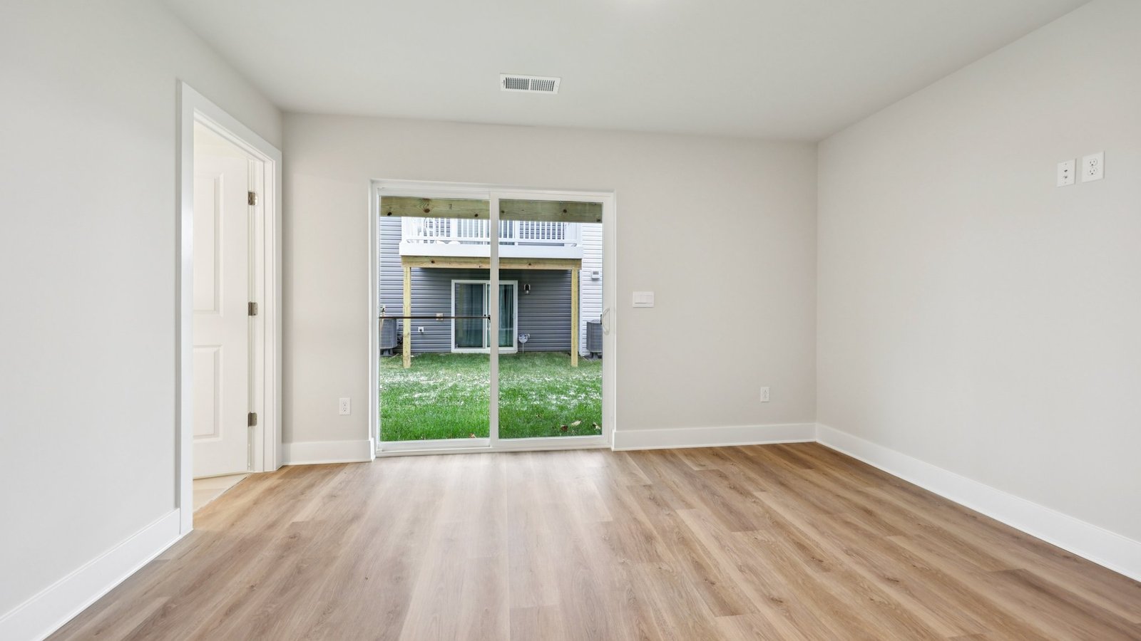 Bedroom — queen bed with gray accent wall, desk by slider doors, and backyard view.