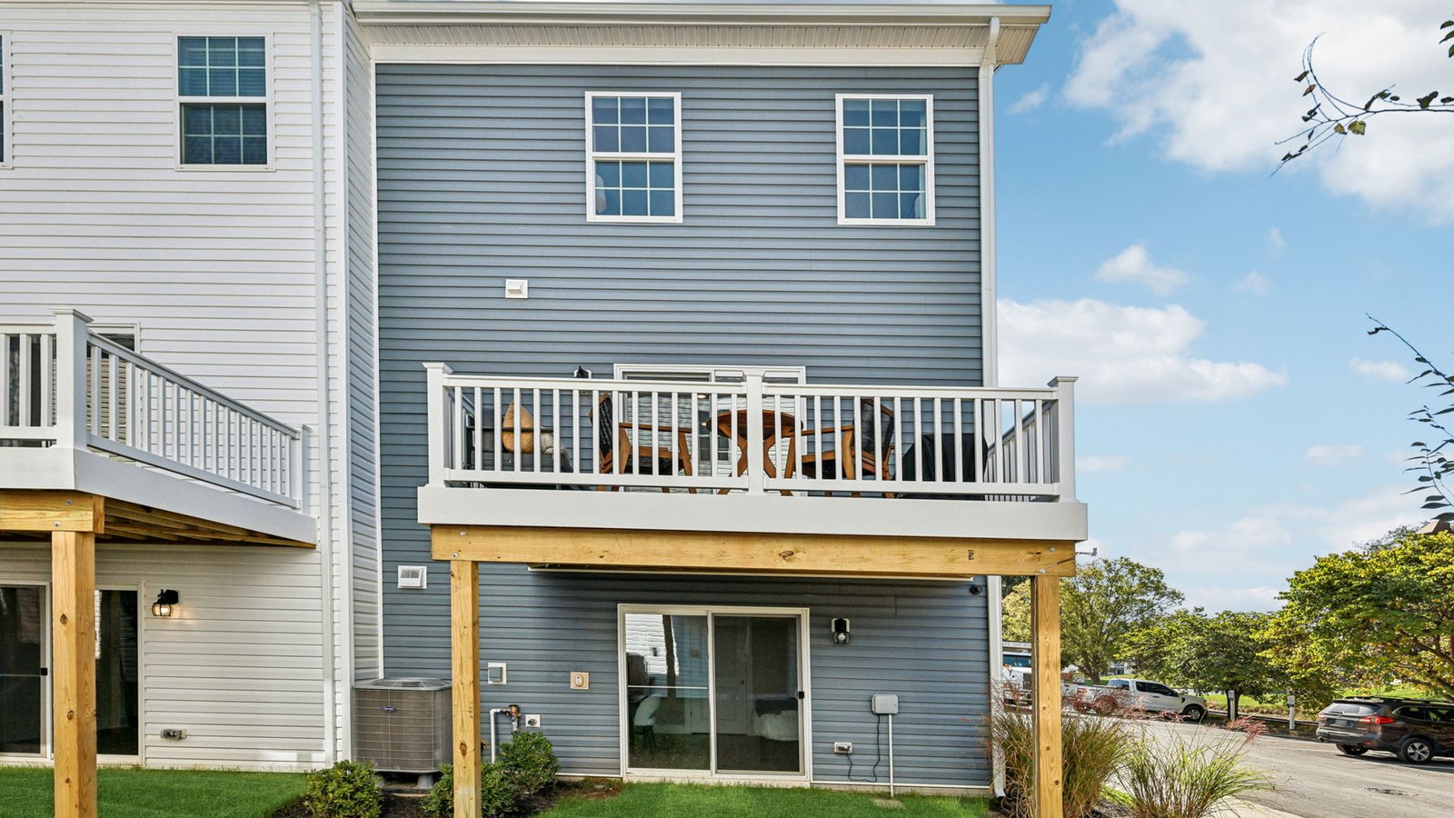 Rear elevation — blue siding with upper deck on posts and walkout patio below.