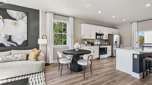 Kitchen and dining — white cabinetry, round table, and island beside window and sliding doors.