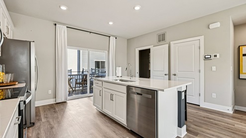 Kitchen — island with sink and pantry doors, slider to the deck.