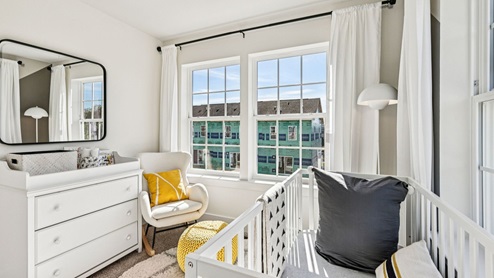 Nursery — changing dresser with mirror, lounge chair, and bright window.