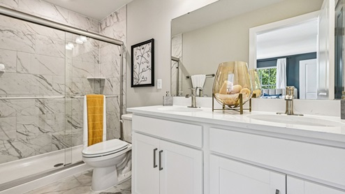 Primary bath — double vanity and large marble‑tile shower with glass doors.