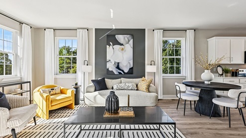 Living room — sofa and yellow accent chair between tall windows with white drapery.