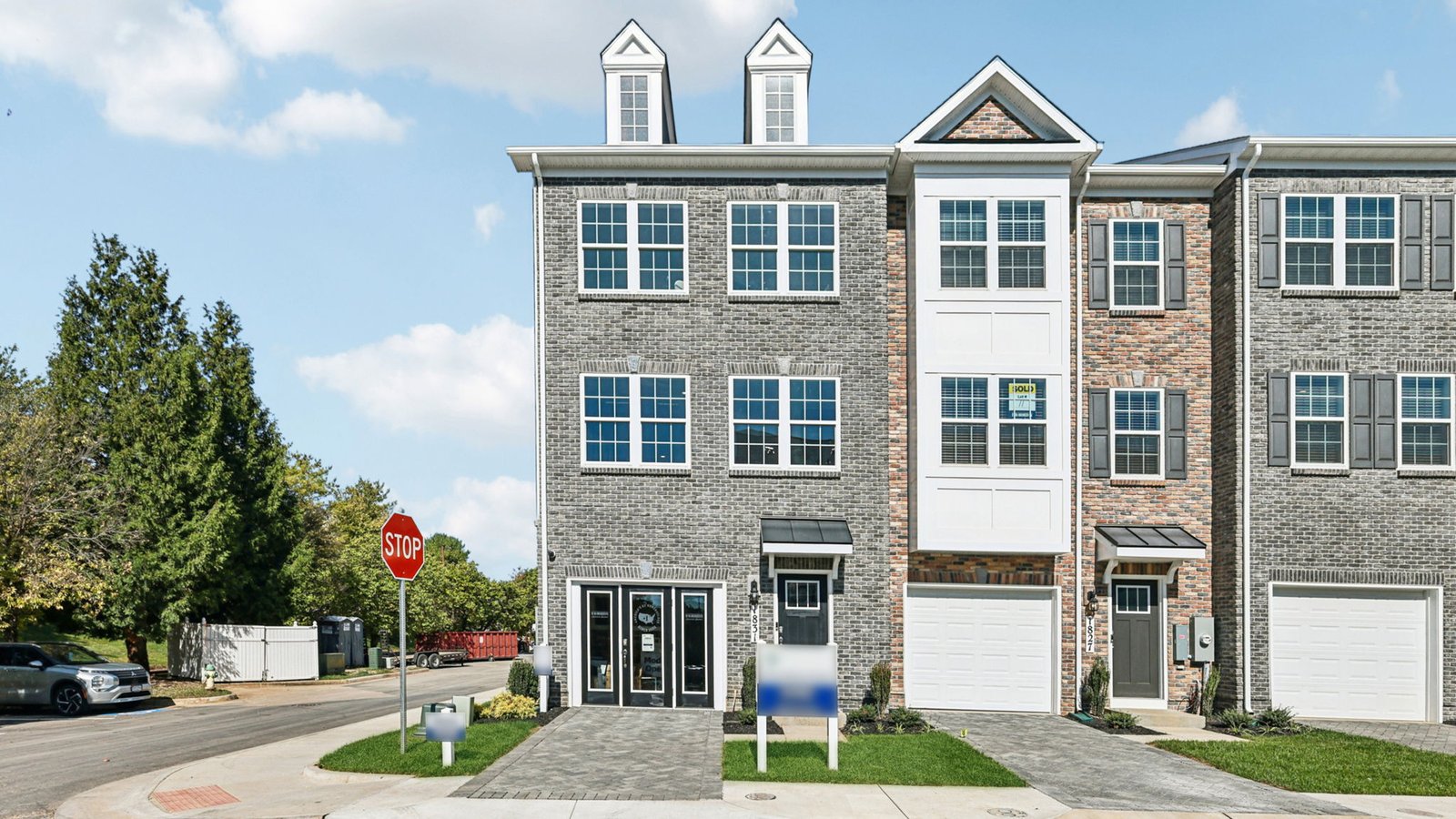 Front exterior — end-unit townhome with brick facade, dormers, and single-car garage.