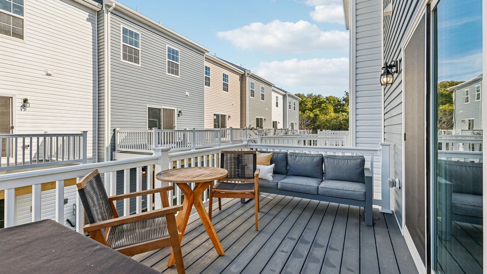 Rear deck — outdoor sofa and chairs with railings overlooking townhomes.