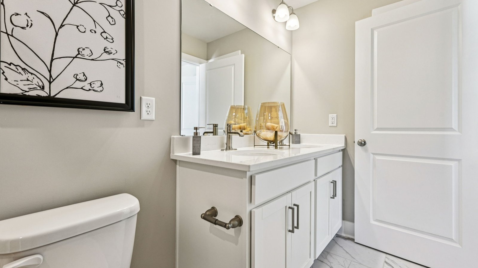 Secondary bath — vanity with wide mirror and decorative glass vases.