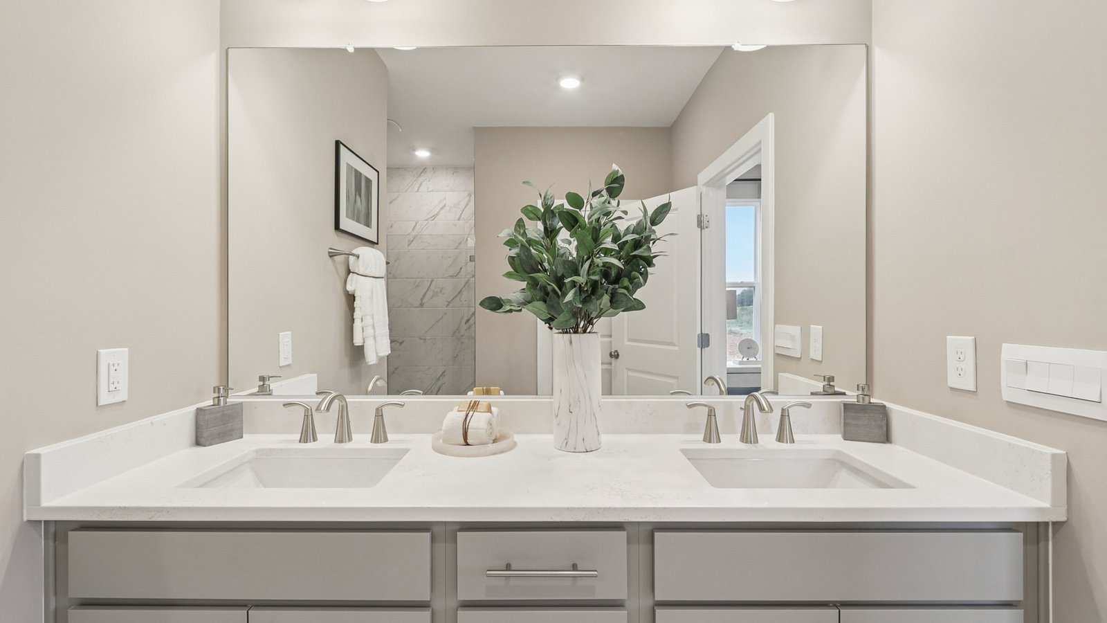 primary bathroom with dual sink vanity and walk in shower on main floor