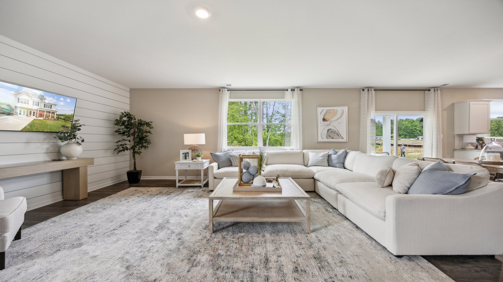 Spacious living room with large windows, natural light, looking to dining, and kitchen areas in this new home