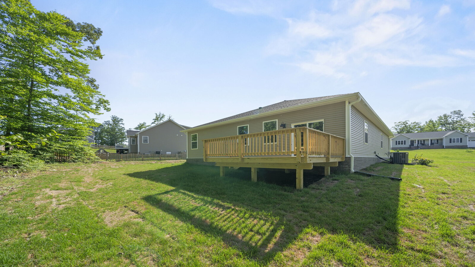 Backyard with new wood deck offering seating, grill setup, green grass and a transition from indoor to outdoor living