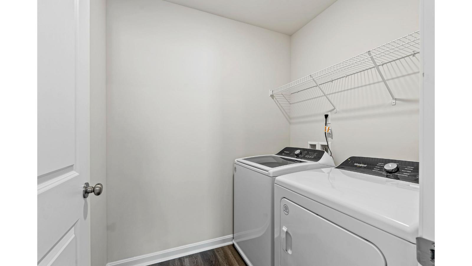 Modern laundry utility room in Arbors at Farms of New Kent  by D.R. Horton with upper shelving and clean finishes