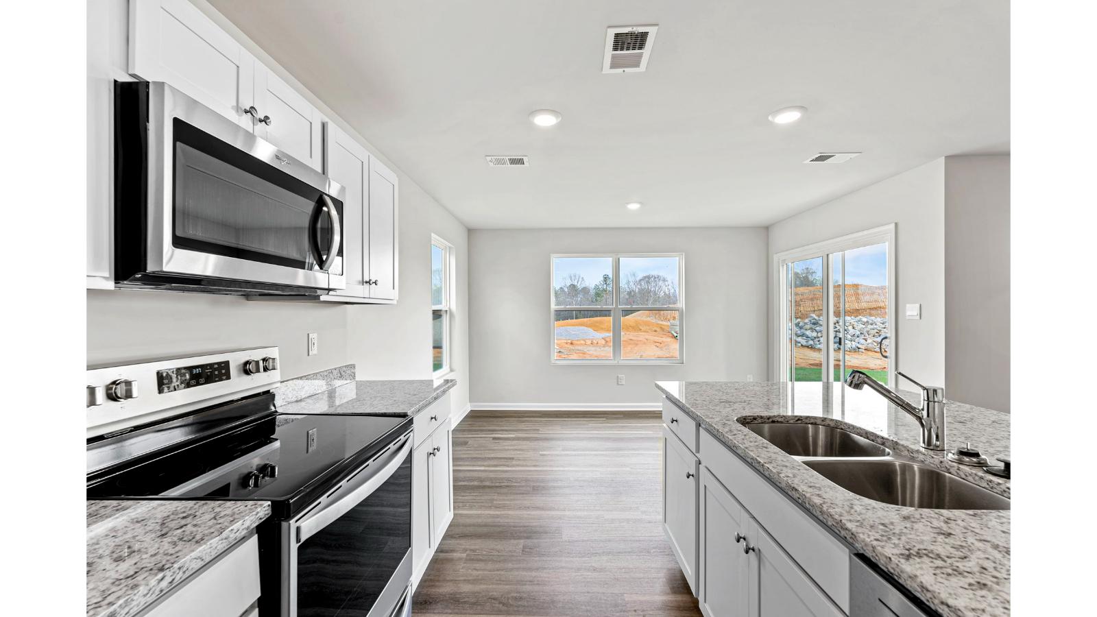 Kitchen island in D.R. Horton layout connects to pantry, dining-living areas with efficient flow and modern surface finishes