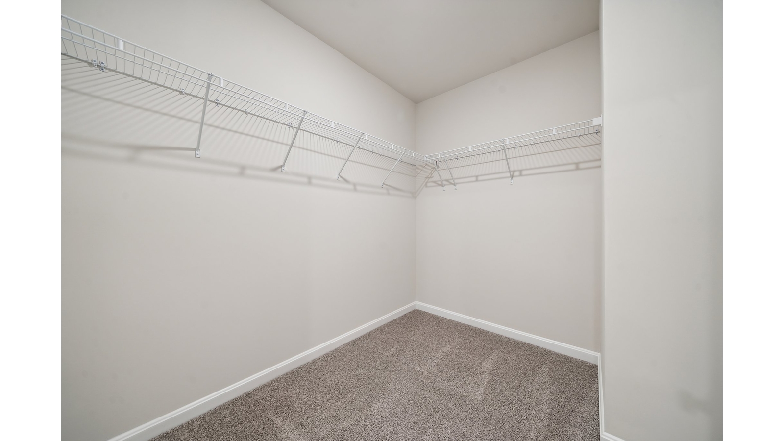 Primary bedroom walk-in closet enjoys ample space for clothes and accessories in Arbors at Farms of New Kent