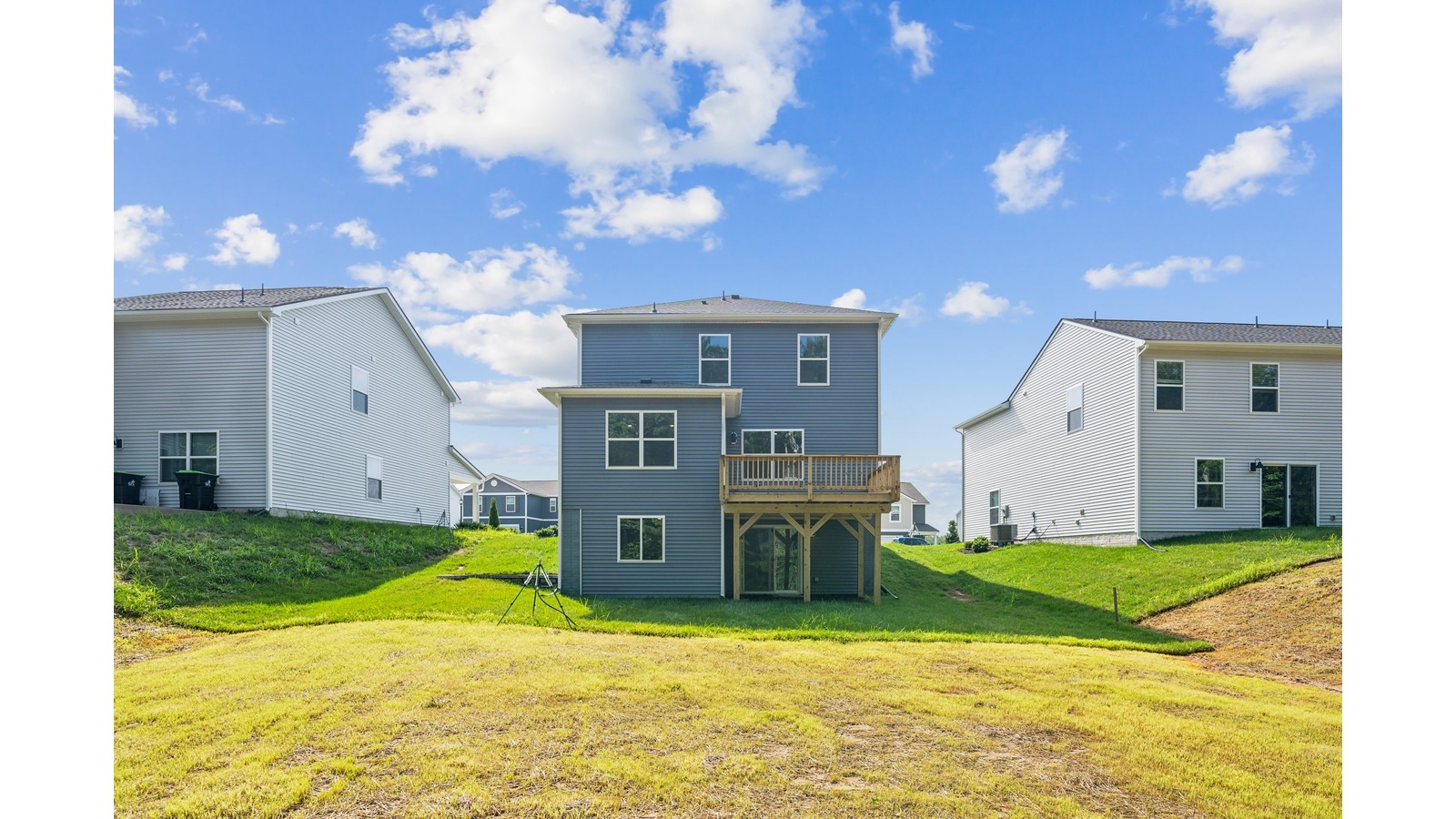 Outdoor living area by includes back deck, concrete rear patio, flat backyard, and rear-facing windows from the main level