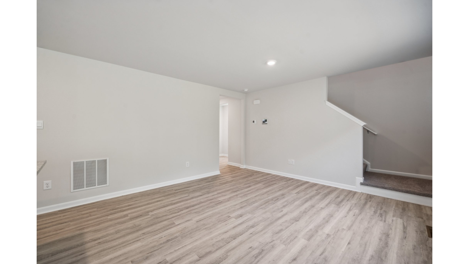 Modern kitchen with hard surface island, brand-new appliances, LED recessed lighting near upstairs access