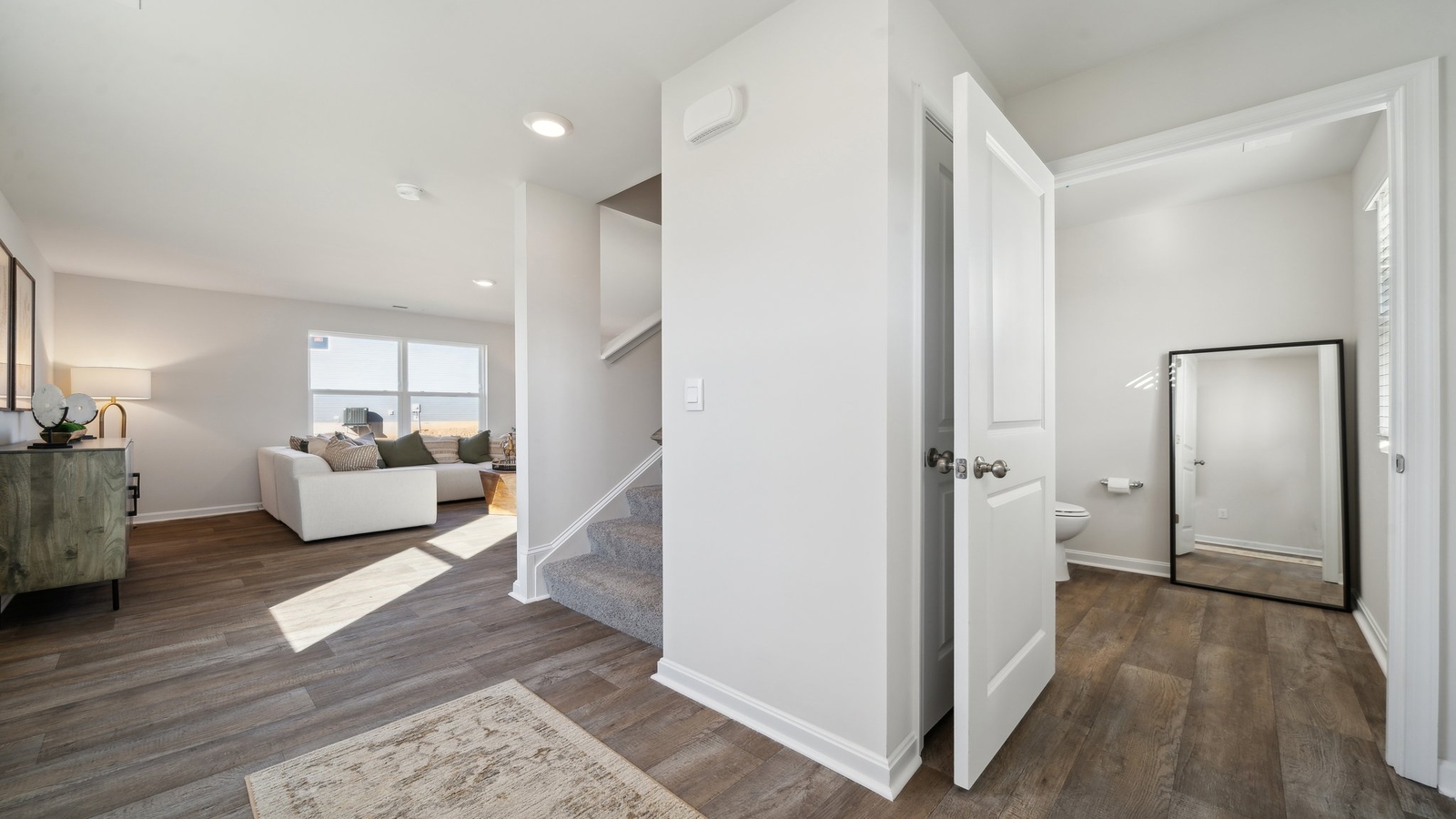 Half bath with white pedestal sink, single-lever faucet, and wall-mounted mirror in Arbors at Farms of New Kent  near front