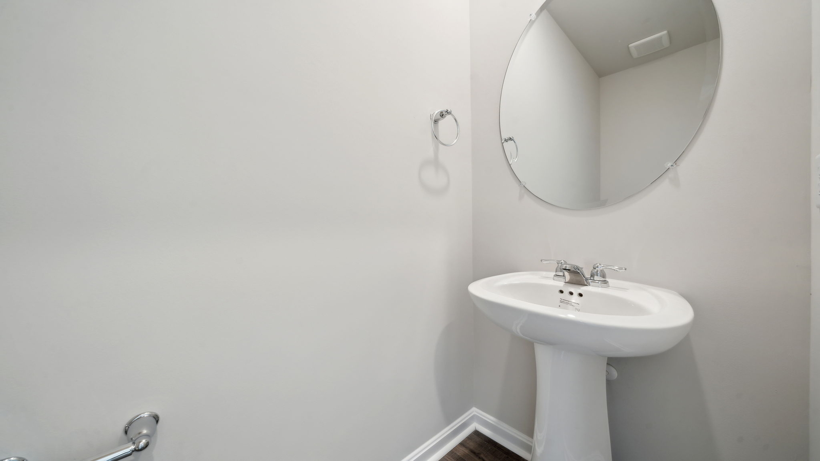 Half bathroom near main living area with mirror and pedestal sink at Arbors at Farms of New Kent by D.R. Horton