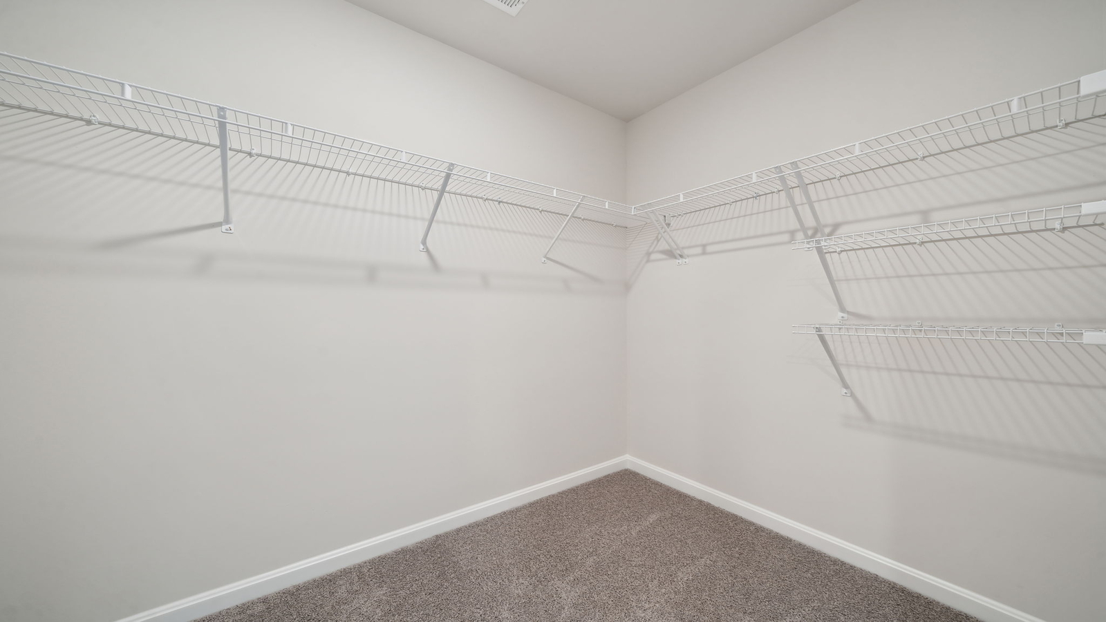 Primary suite walk-in closet in Arbors at Farms of New Kent new home with built-in shelving and generous storage space