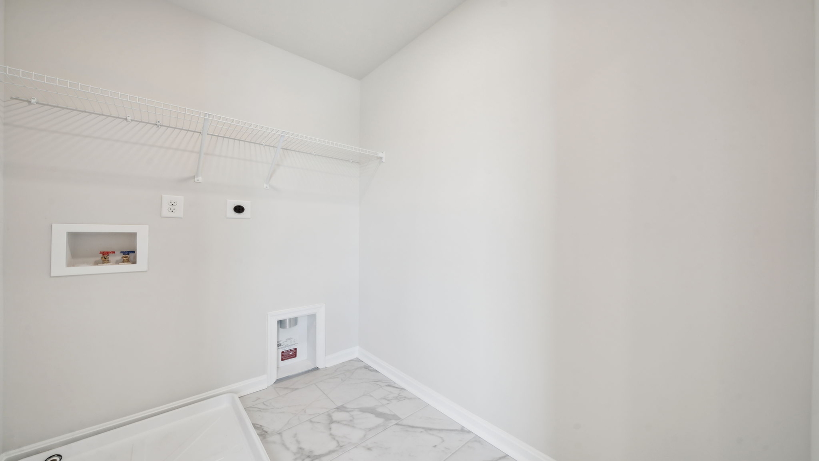 New construction laundry room at Arbors at Farms of New Kent includes overhead storage and modern finishes