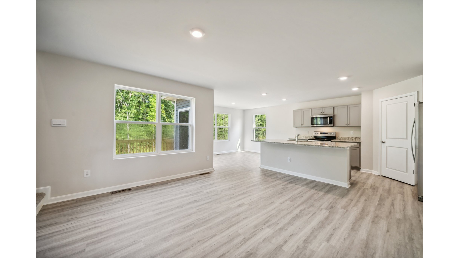 Kitchen island facing open-concept main living area with dining and family room access at Arbors at Farms of New Kent