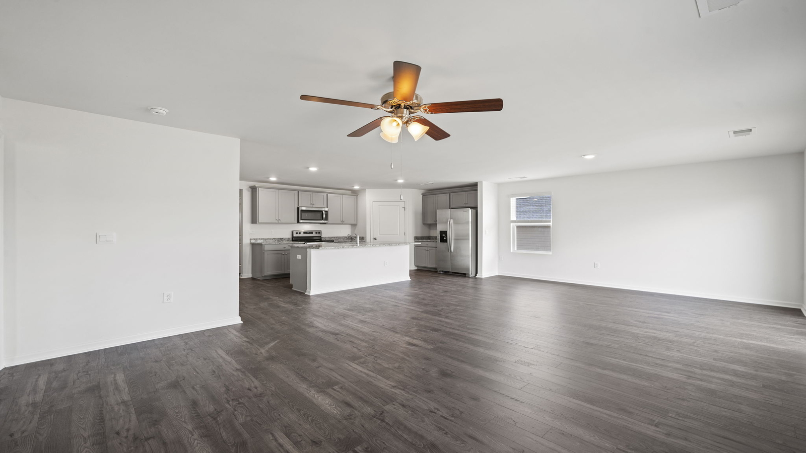 Wide view from living room showing kitchen island, pantry entry, and stair design at Chappell Creek