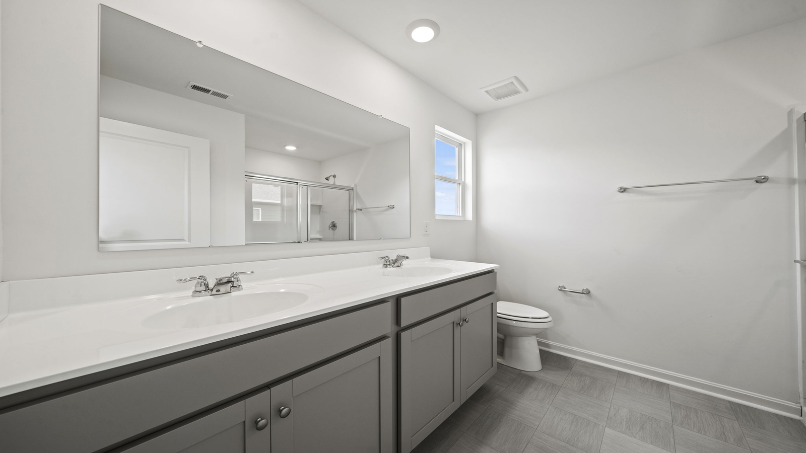 Primary ensuite bathroom in D.R. Horton's new home featuring an expansive vanity with dual sinks, shower, tub, walk-in closet