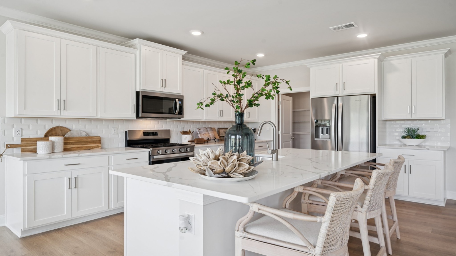 Functional island kitchen with seating, durable countertops, modern LED lighting, and connected dining area in D.R. Horton floorplan.