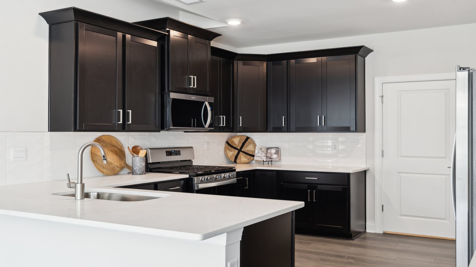Functional island kitchen with seating, durable countertops, modern LED lighting, and connected dining area in D.R. Horton floorplan.