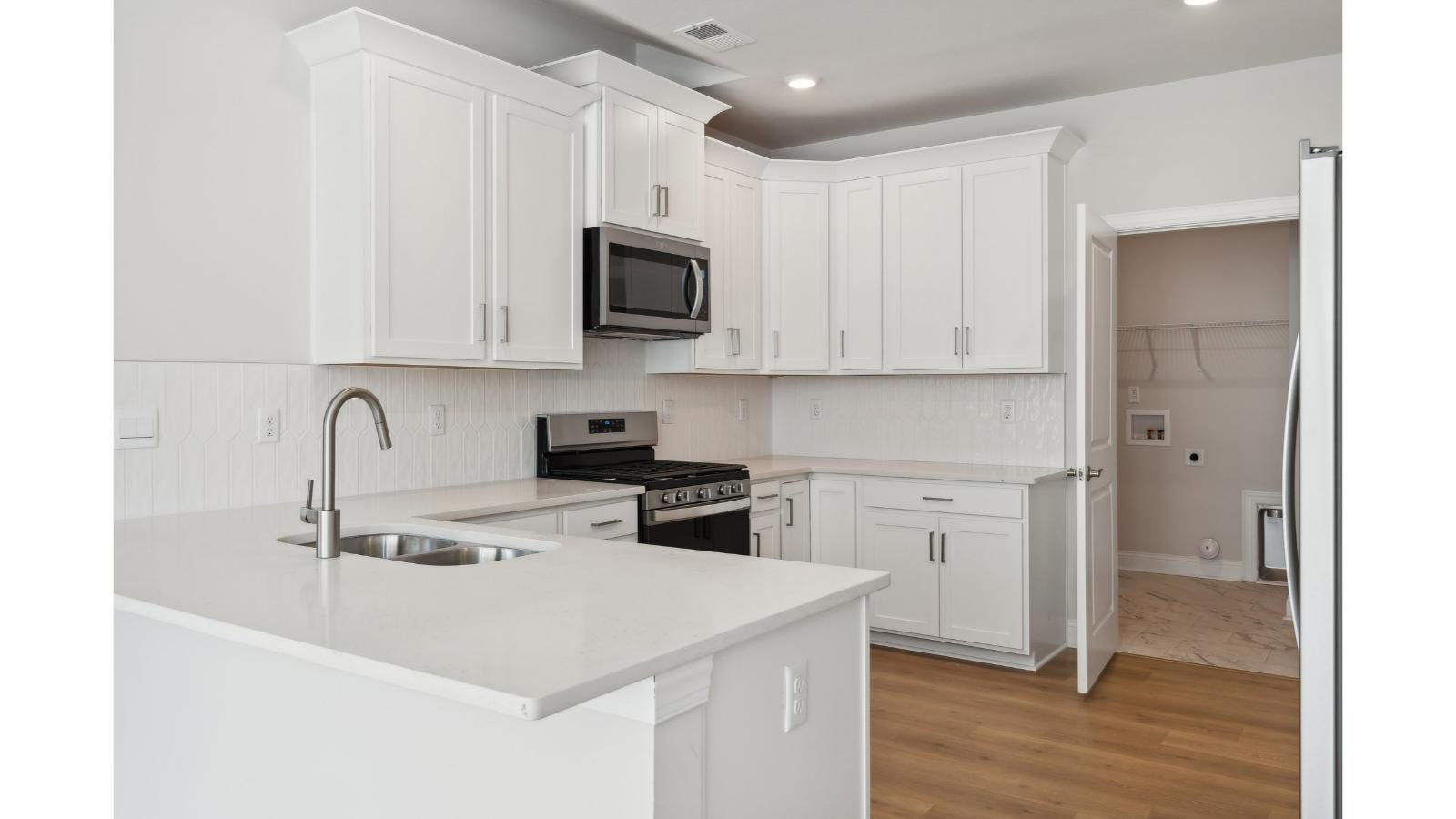 Kitchen island in this D.R. Horton New Home featuring seating, storage, pantry and a New appliance suite