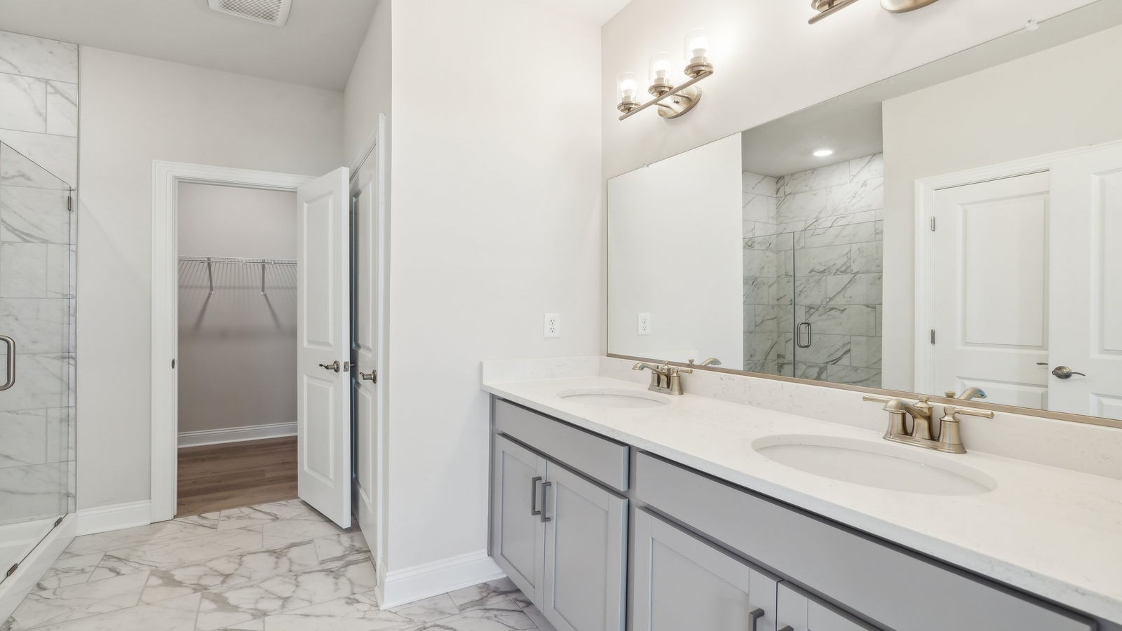 Primary bathroom in this New Build Home includes extended vanity, quality cabinets, walk-in closet and spa-style layout