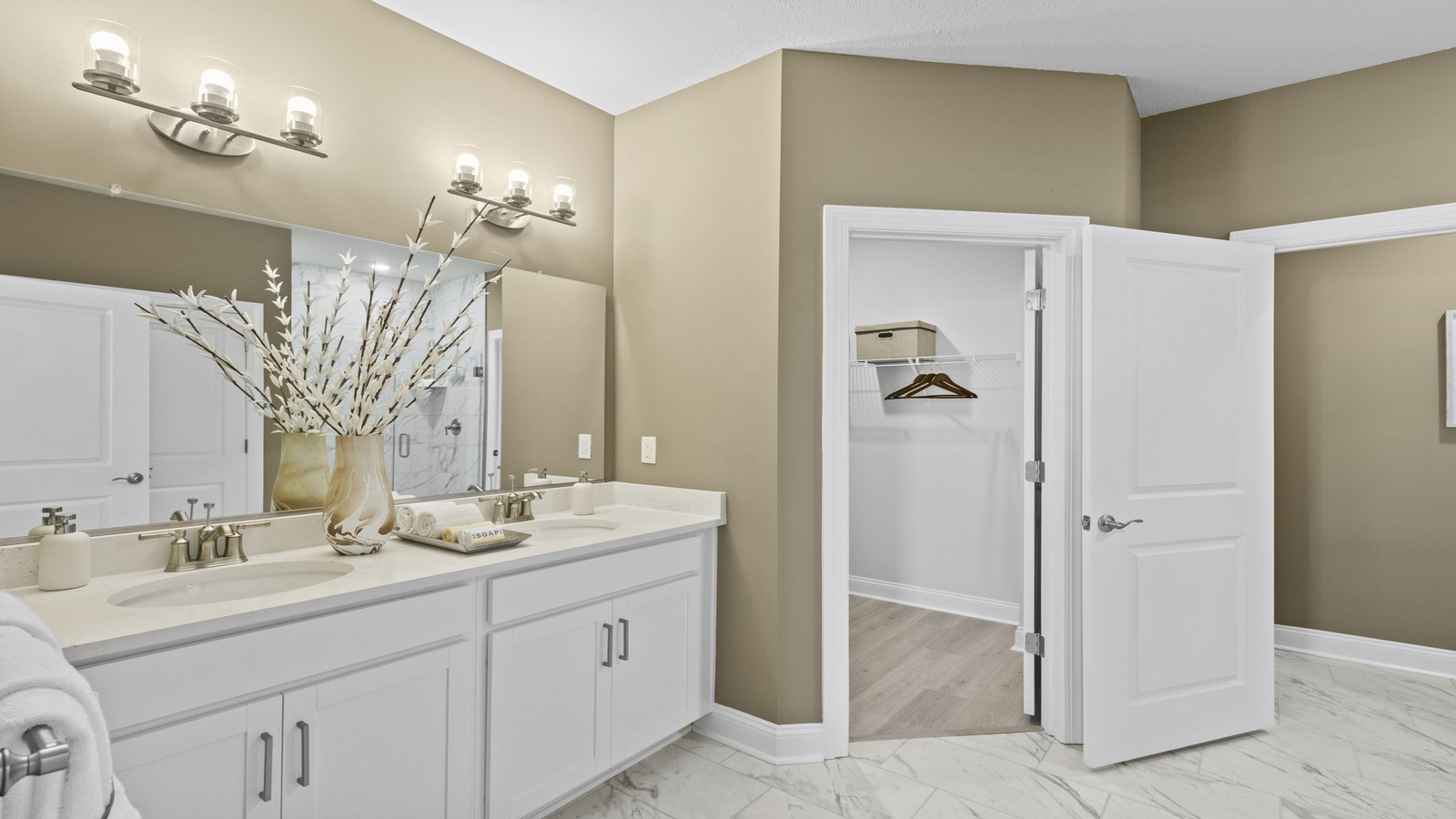 Primary bathroom in this New Build Home includes extended vanity, quality cabinets, walk-in closet and spa-style layout