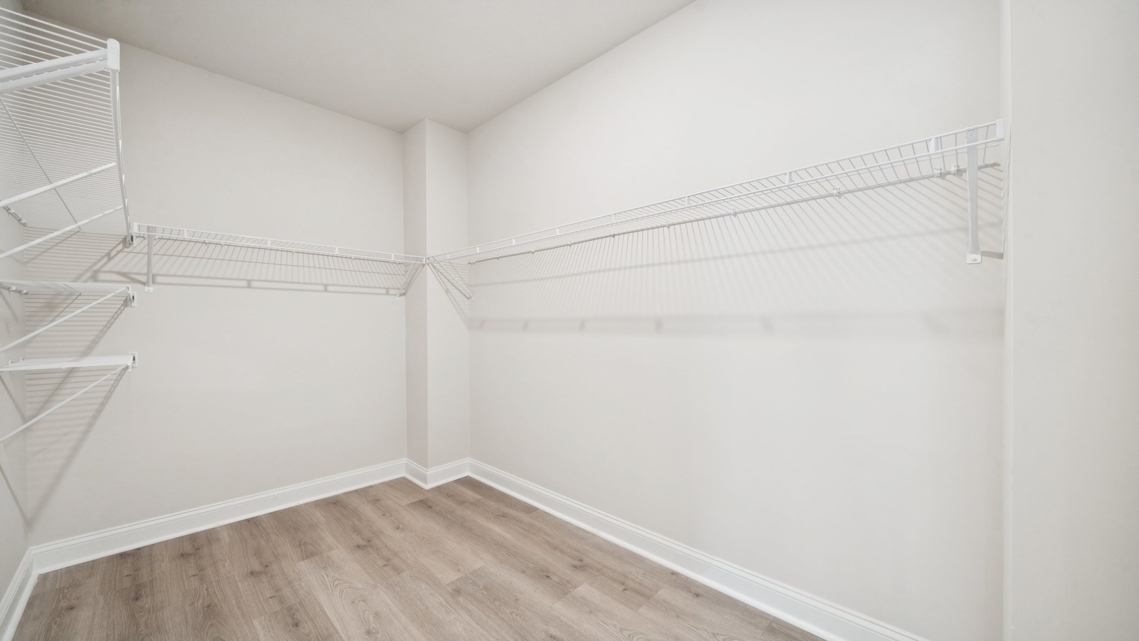 Primary suite walk-in closet in Country Club Villas new home with built-in shelving and generous storage space