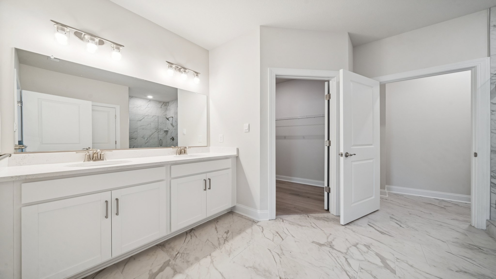 D.R. Horton ensuite design with step-in shower, bright overhead lighting, walk-in closet, open access from the primary bedroom