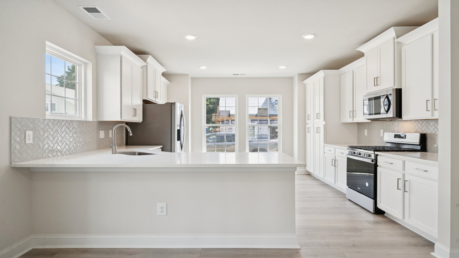 New Home kitchen island with bar seating, ample storage and pantry, and new appliance suite and cooking zone