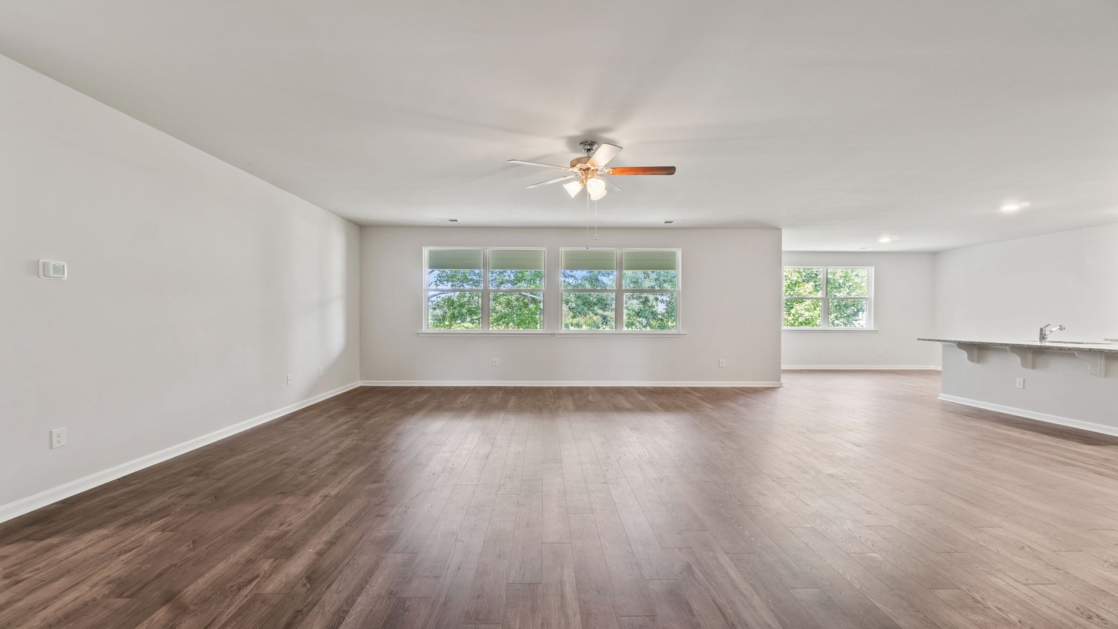 Living room in this New Construction Home features quality flooring, LED lighting, a Fresh Open Concept flow to the kitchen