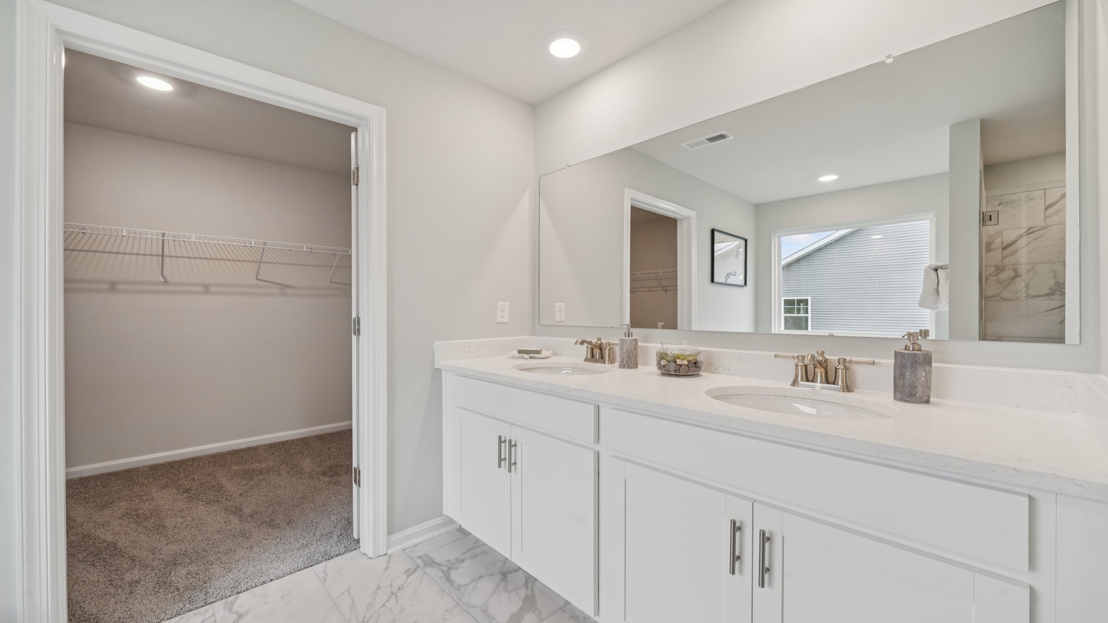 Primary bathroom in this New Build Home includes extended vanity, quality cabinets, walk-in closet and spa-inspired design