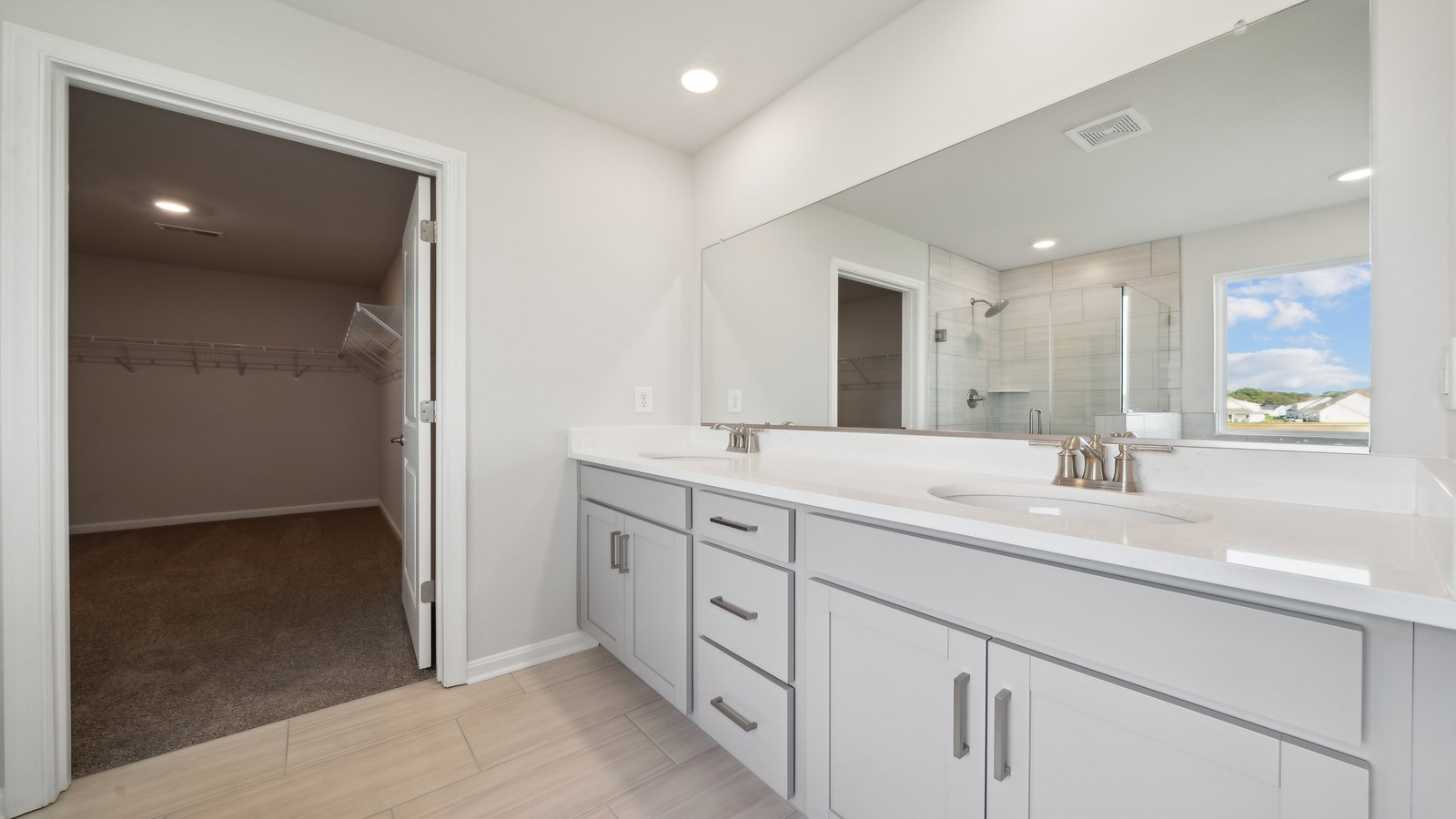 Primary bathroom in this New Build Home includes extended vanity, quality cabinets, walk-in closet and spa-inspired design