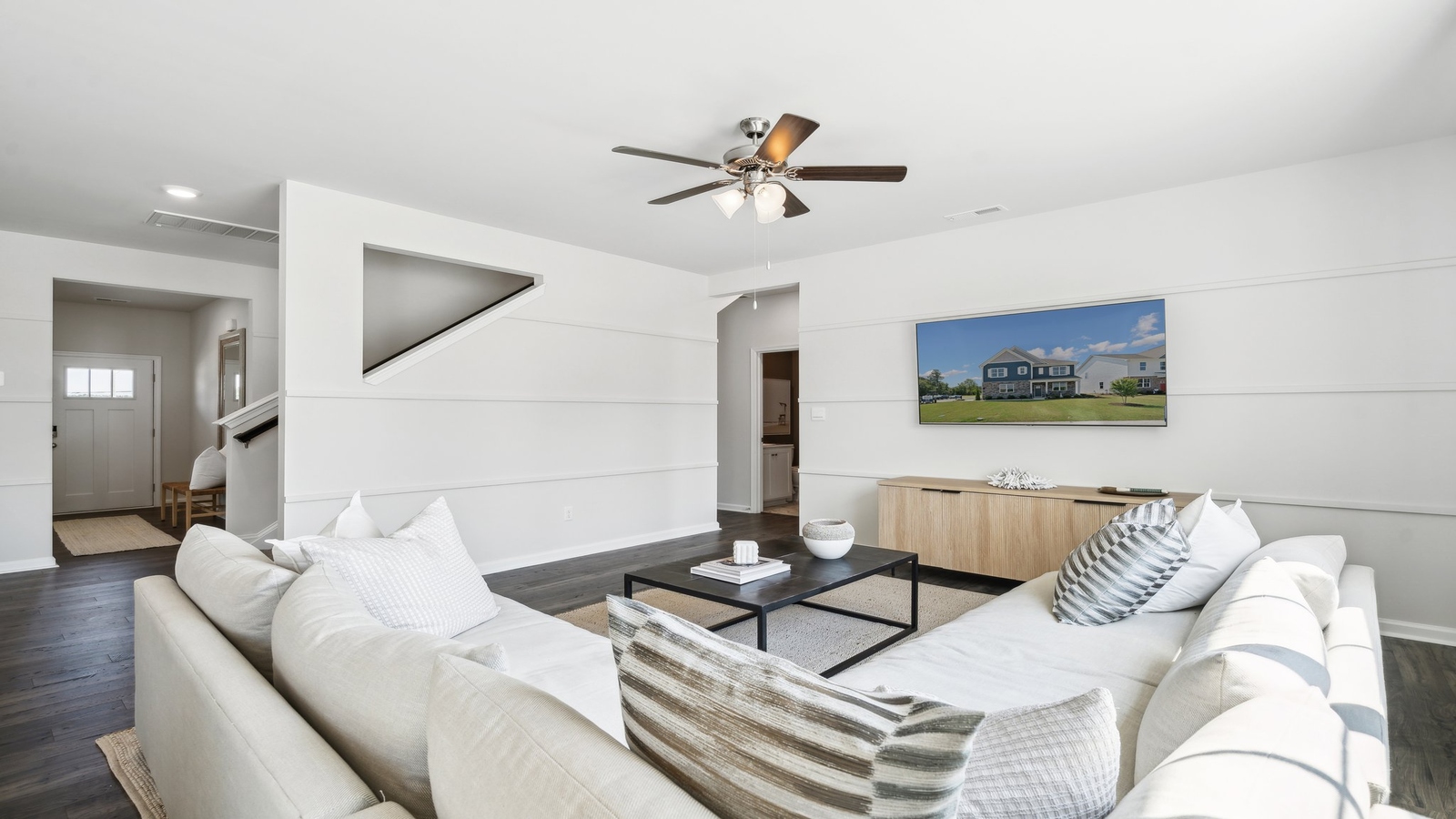 Living room designed by D.R. Horton showcases central access to kitchen, dining, living, upstairs, bedrooms, rear patio