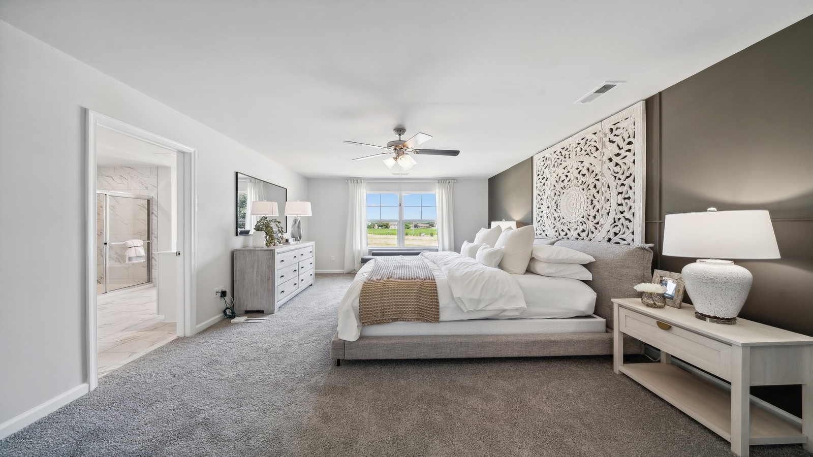 Primary bedroom in this New Home features ample space, double windows, quality carpet, walk-in closet, and a private ensuite bath