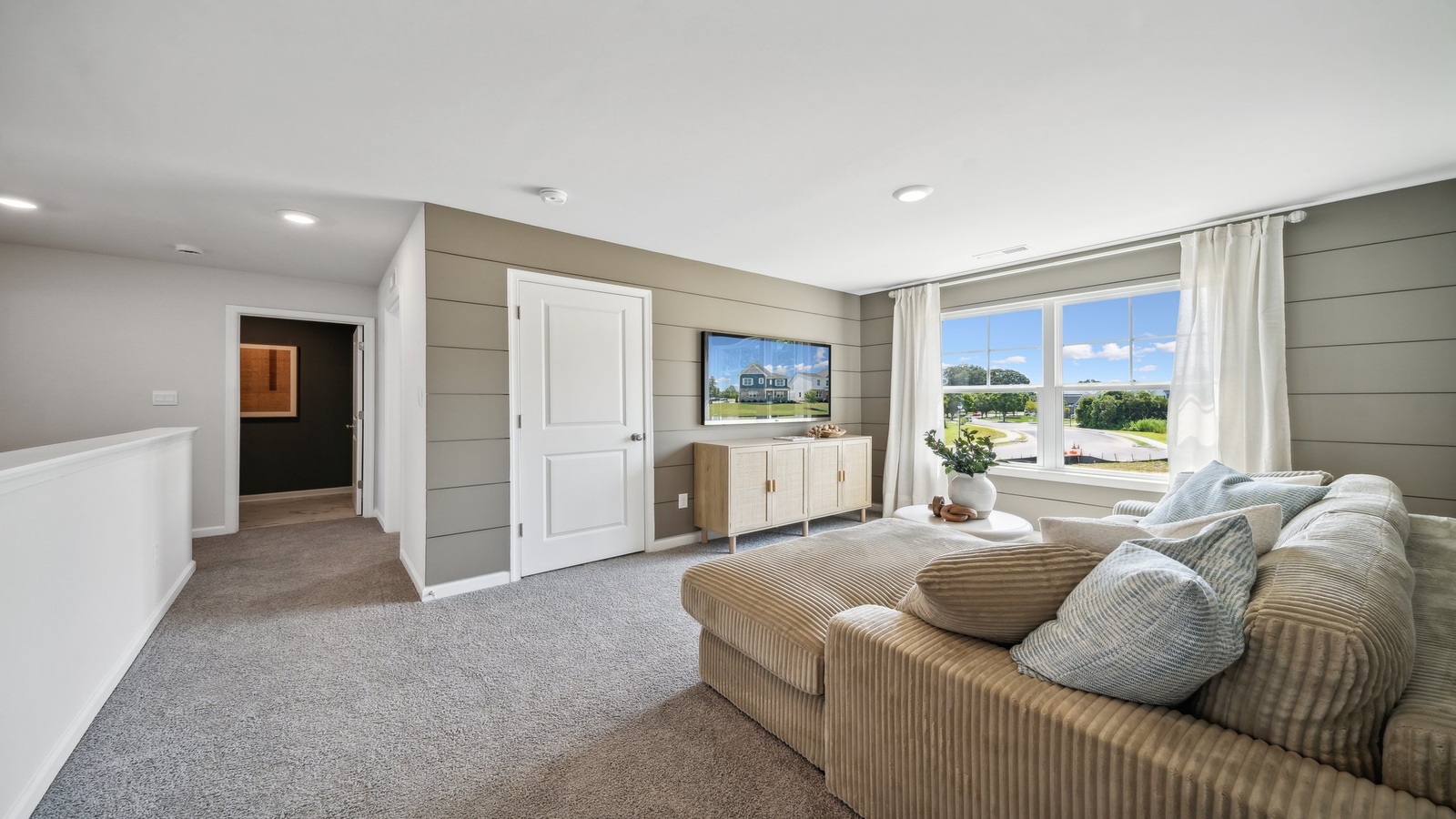 Bright loft space with carpet flooring near secondary bedrooms