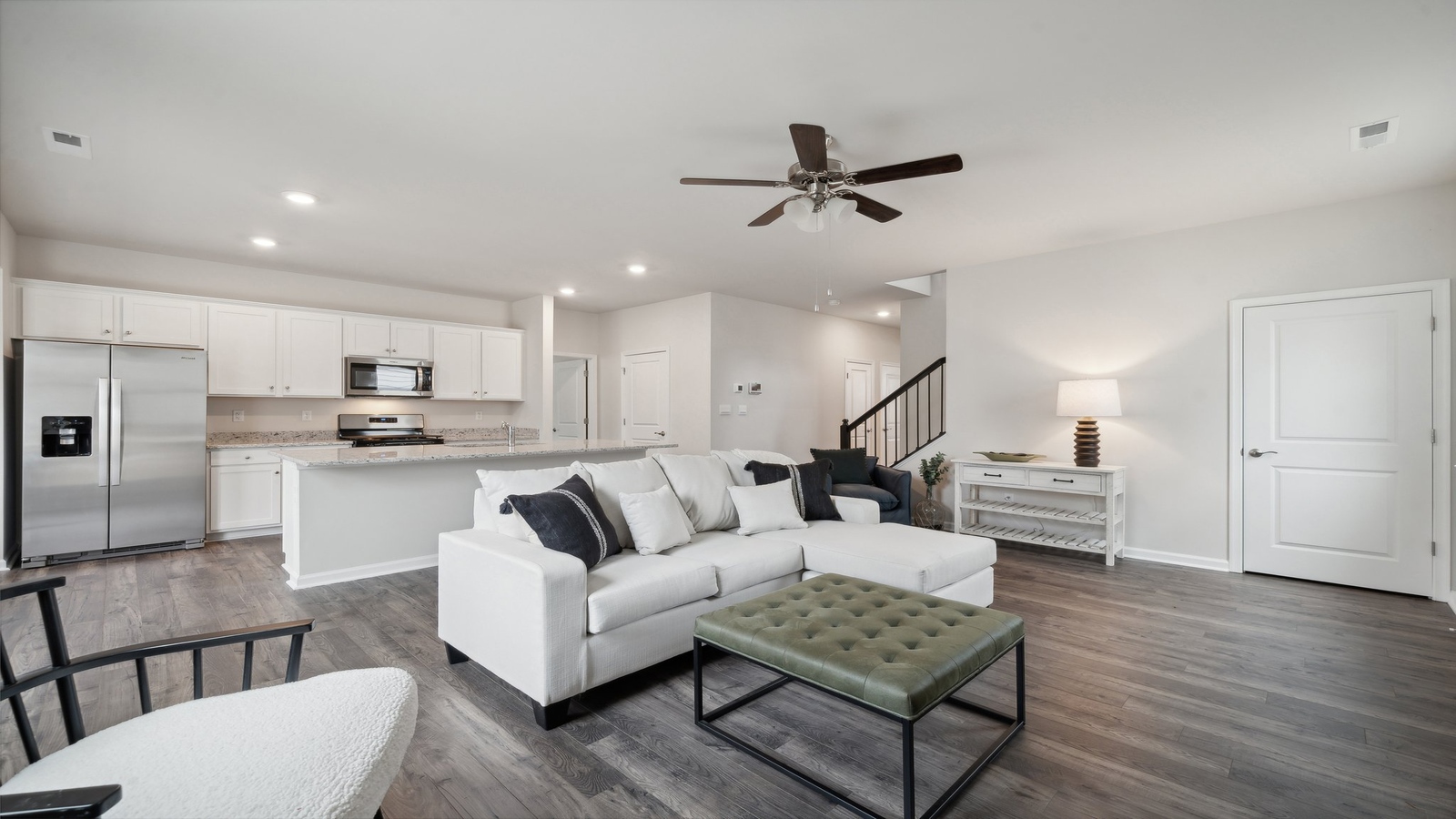 Spacious great room looking toward modern kitchen with island, new appliances at Bennetts Pasture