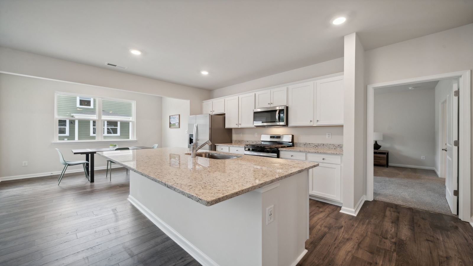 Functional layout with family room looking into modern kitchen and stairwell to upper bedrooms at Bennetts Pasture