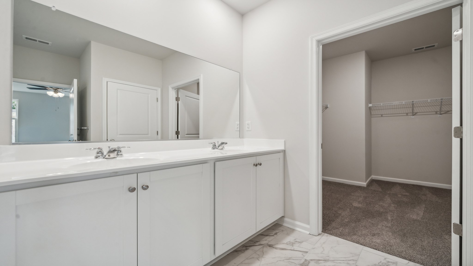 Primary ensuite bathroom in this D.R. Horton new home featuring expansive vanity with dual sinks, shower-tub, walk-in closet