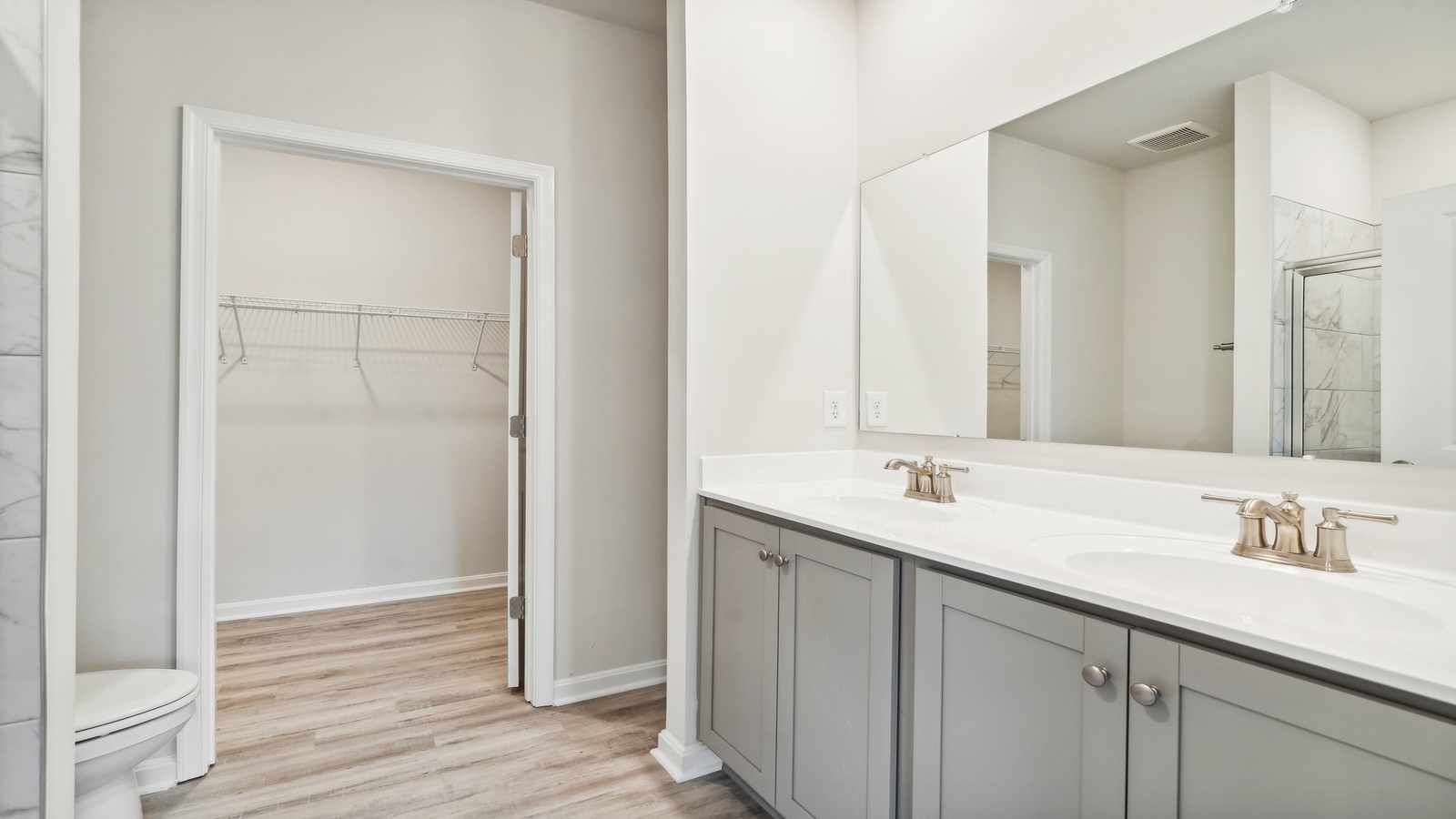 Primary ensuite bathroom in D.R. Horton's new townhome featuring an expansive vanity with dual sinks, shower, tub, walk-in closet