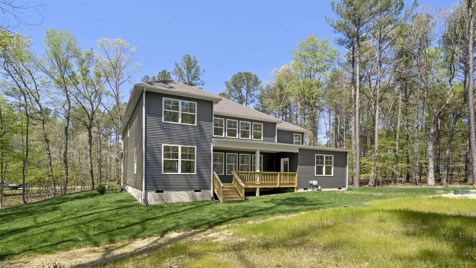 Backyard in this New Home with full lawn, covered deck, and fencing potential for added privacy