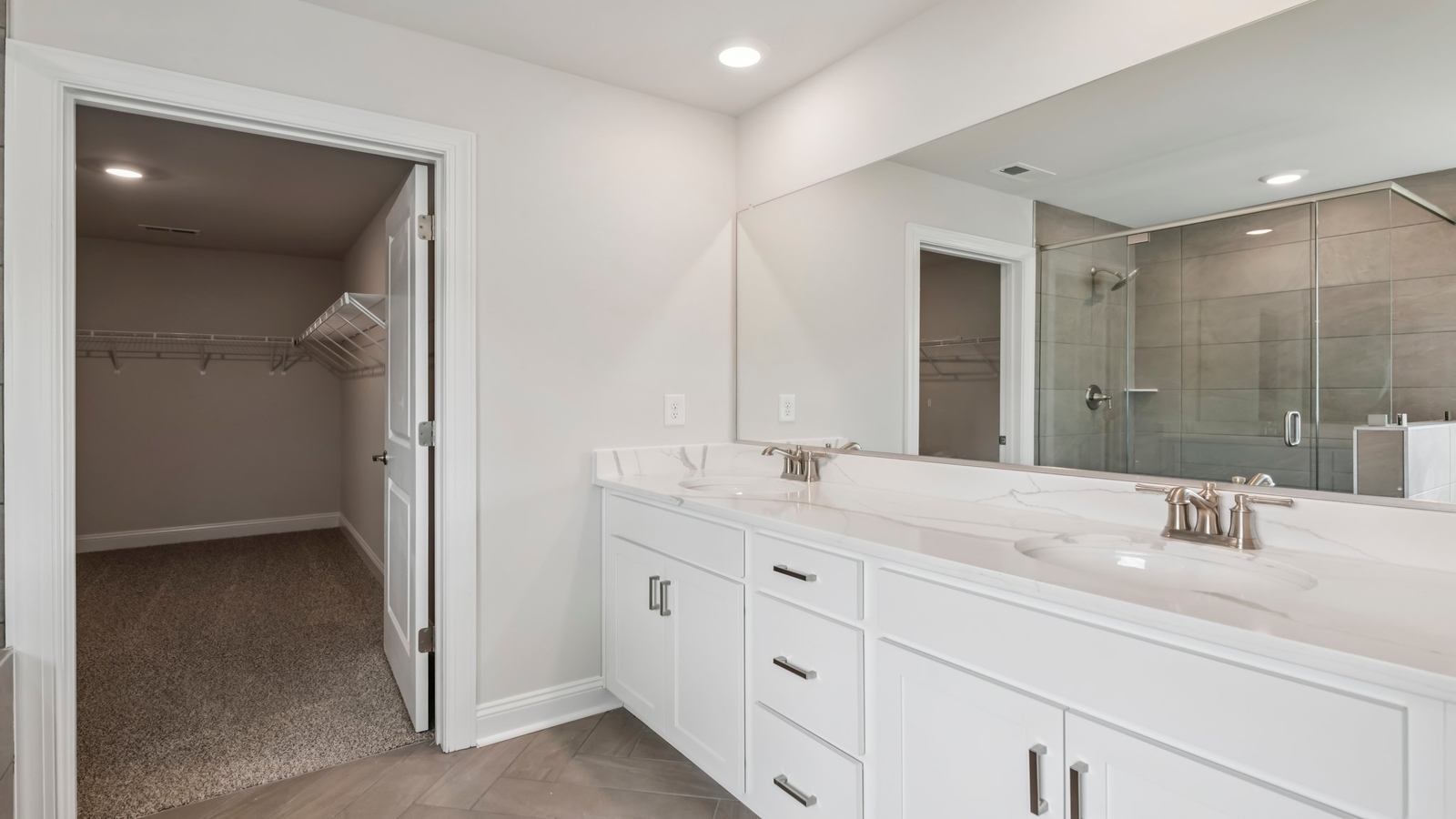 Primary bathroom in this New Build Home includes extended vanity, quality cabinets, walk-in closet and spa-inspired design