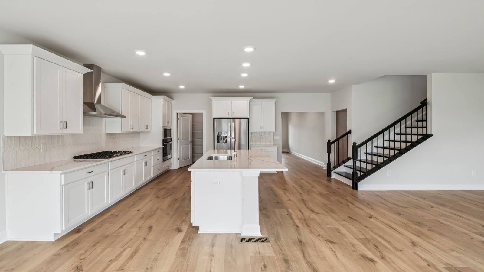 Kitchen island facing open-concept main living area with dining and family room access at Sheppard Mill