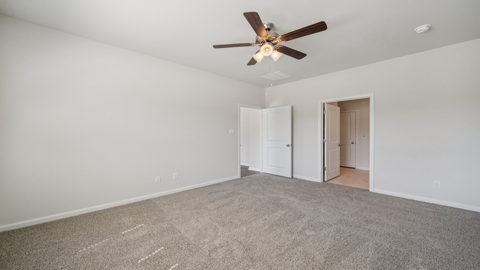 Primary suite at Smith Farm enjoys window views, walk-through access to spa-inspired ensuite bathroom, walk-in closet