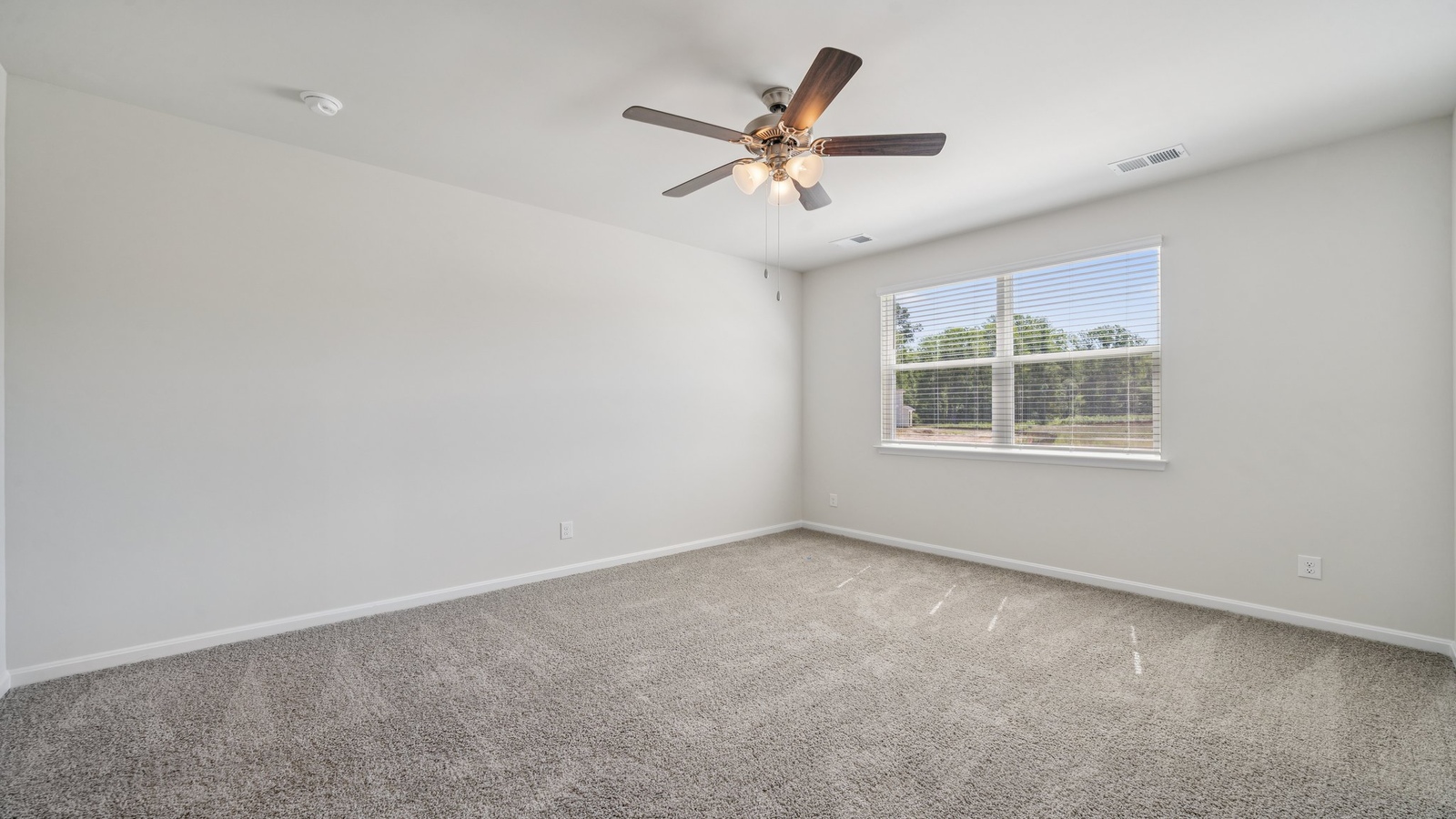 Primary suite at Smith Farm enjoys window views, walk-through access to ensuite bathroom, walk-in closet