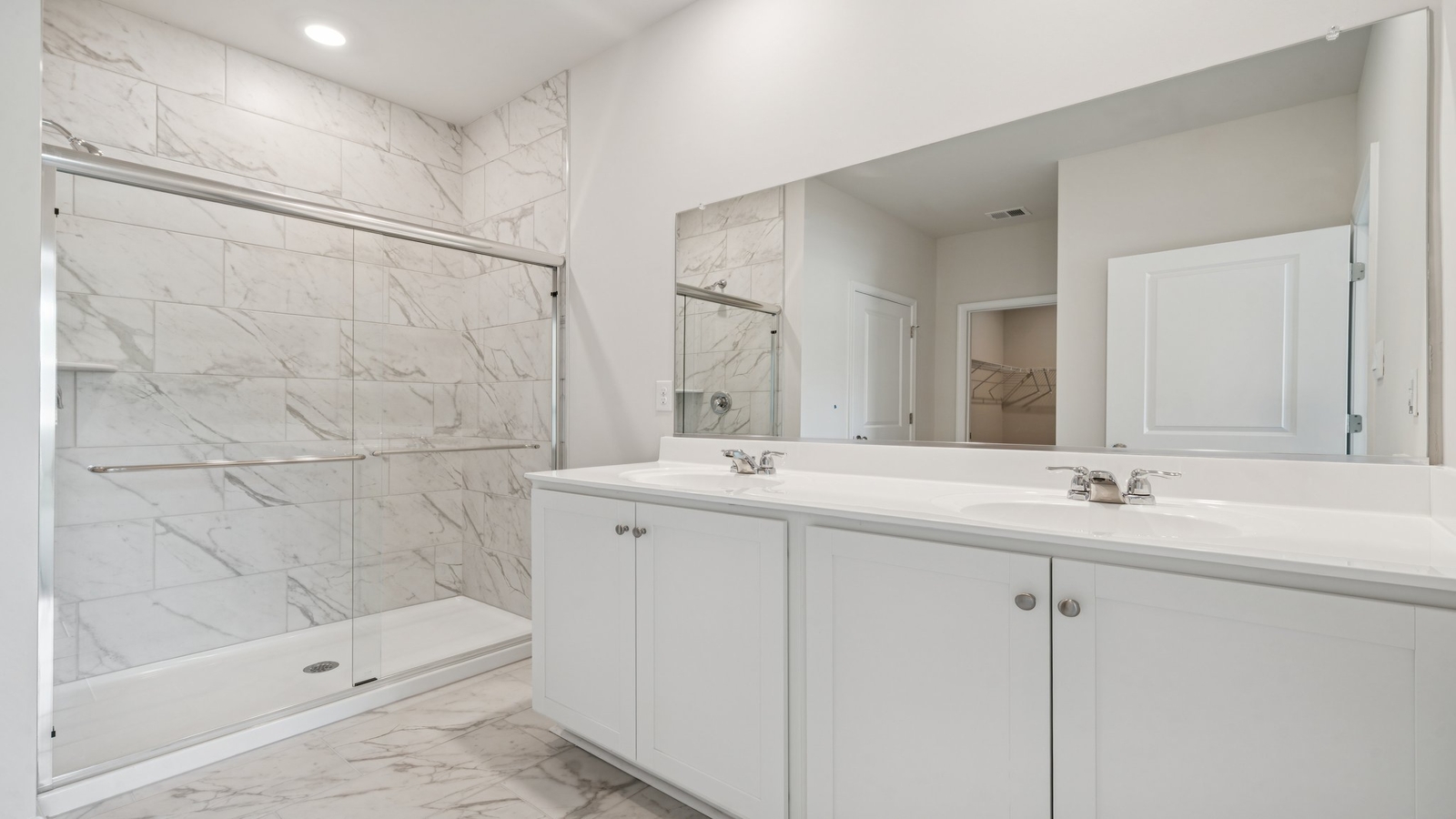 Primary bathroom in this New Build Home includes extended vanity, quality cabinets, walk-in closet and spa-inspired design